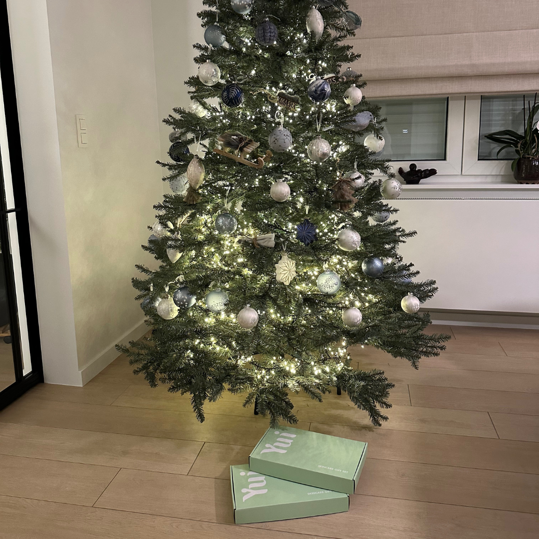 Mint-green Yui Skin gift boxes under a decorated Christmas tree with glowing lights, perfect for holiday gifting.
