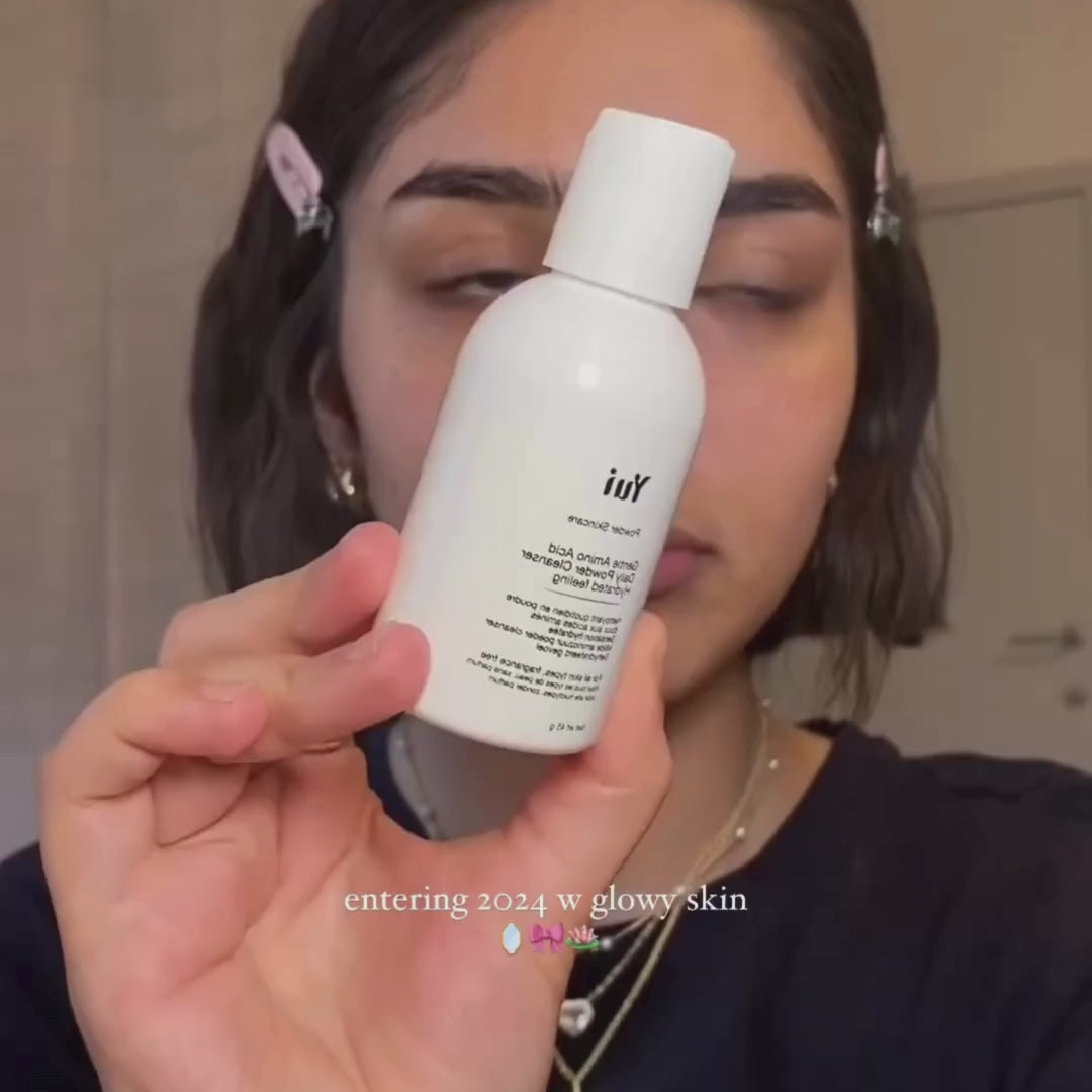 Persoon die de fles Yui Powder Cleanser vasthoudt